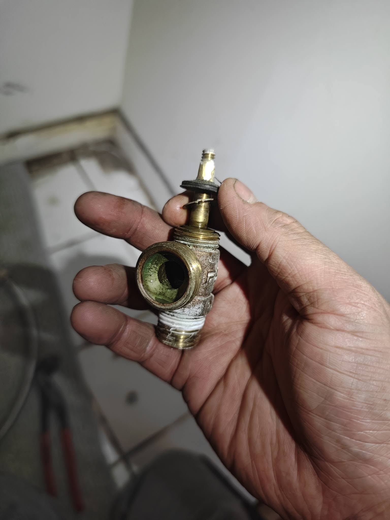手持拆下的閥芯及閥座，可見造成滲漏的內部磨損零件。